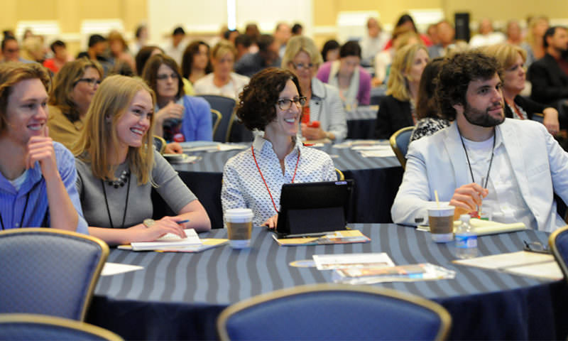 A lot of smiling people in a large meeting room